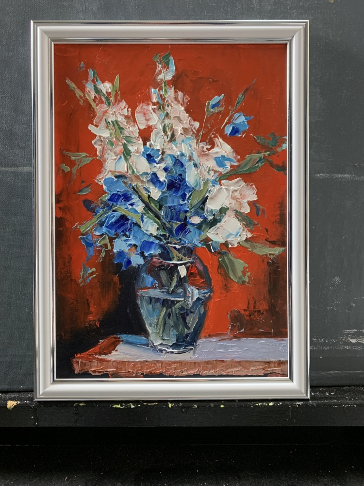 Bouquet of White flowers and bluebells in a blue vase on red. Still life.