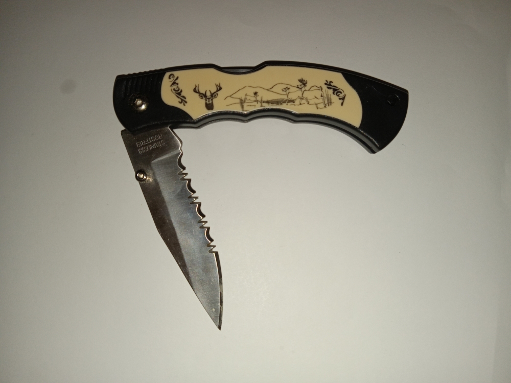 Lockback Knife with single serrated blade and outdoor scenery on side.