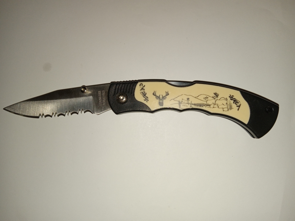 Lockback Knife with single serrated blade and outdoor scenery on side.