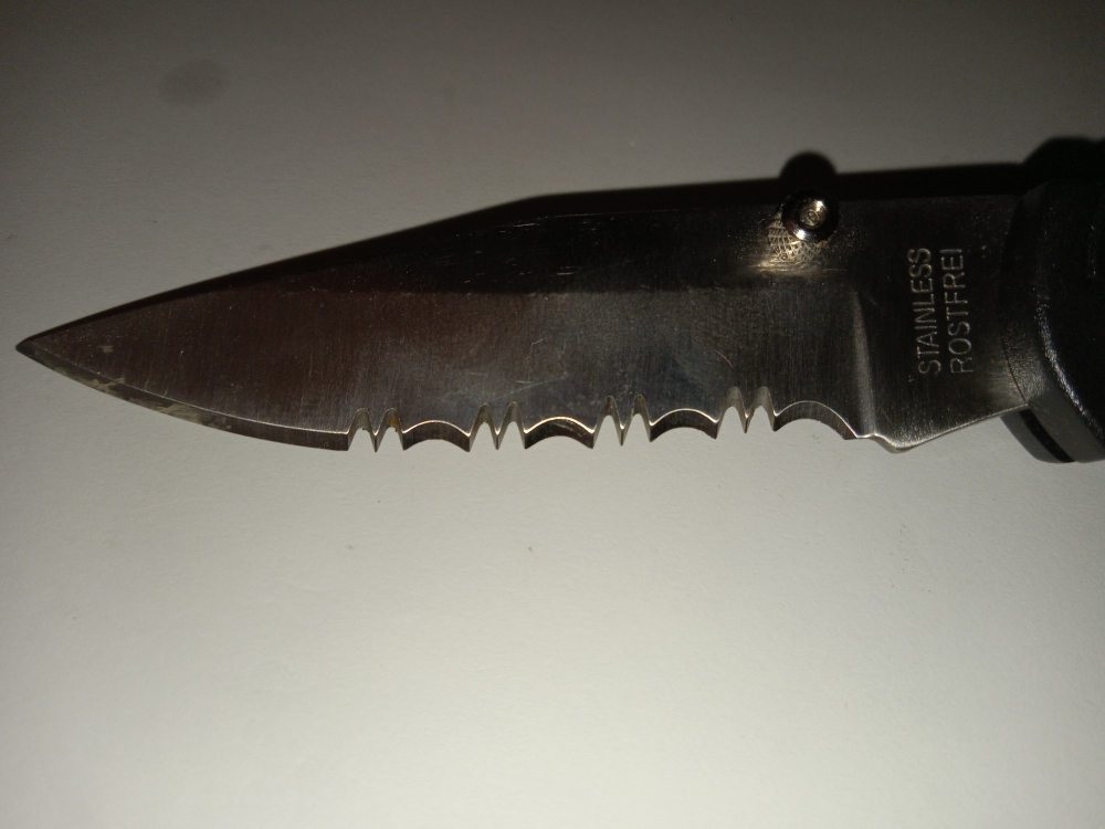 Lockback Knife with single serrated blade and outdoor scenery on side.