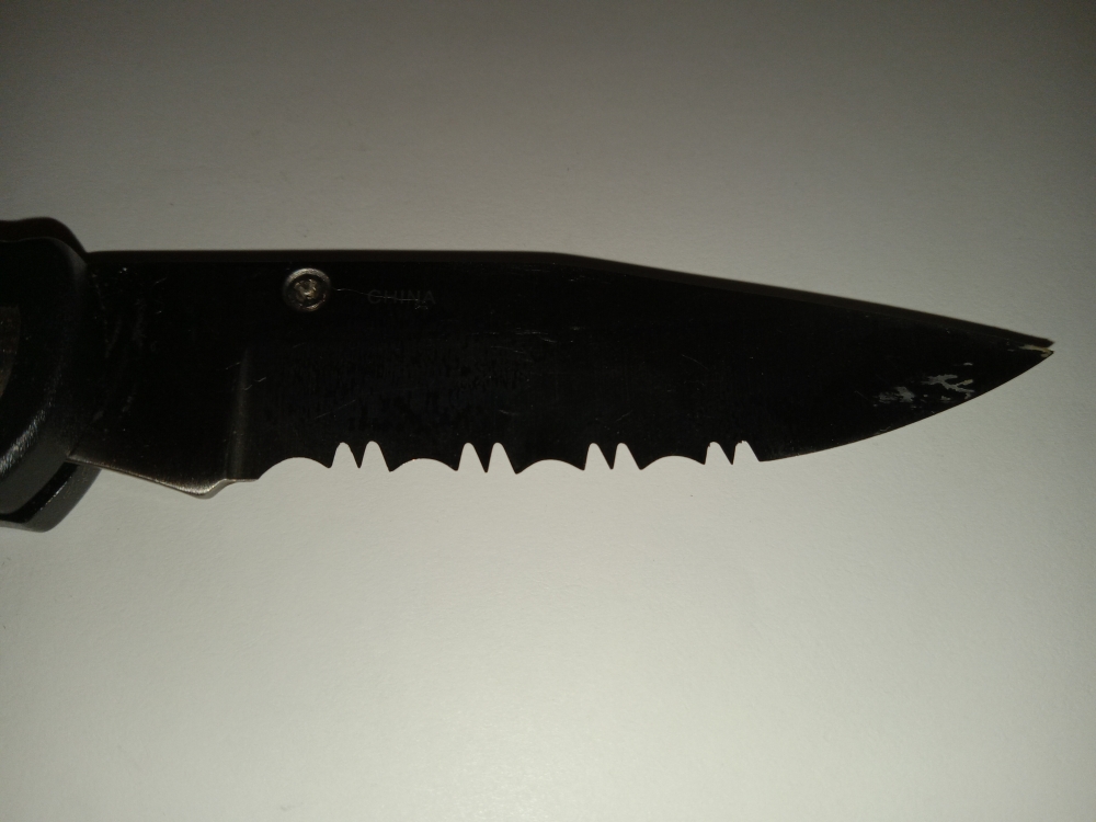 Lockback Knife with single serrated blade and outdoor scenery on side.