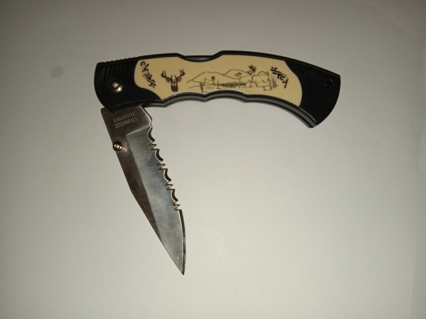 Lockback Knife with single serrated blade and outdoor scenery on side.