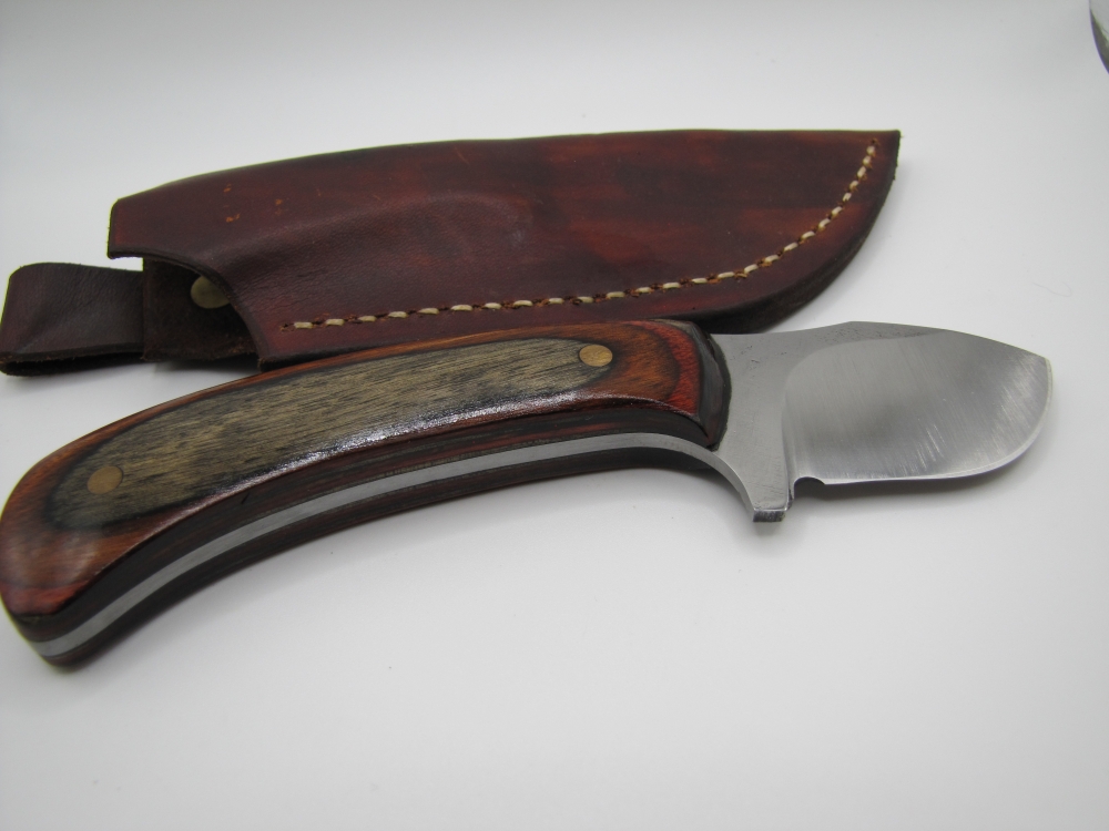 1095 high carbon steel drop point big belly skinner with a red walnut black dymalux handle