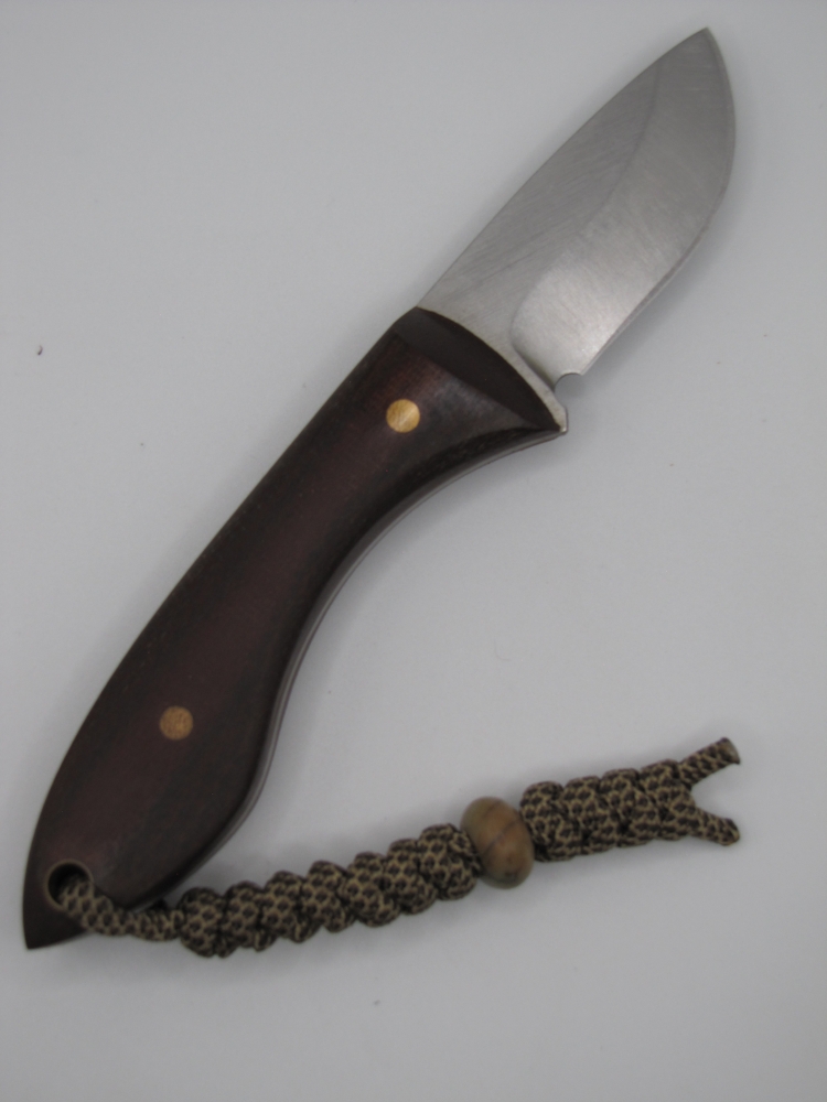 1095 high carbon drop point skinning knife with a red micarta handle with lanyard