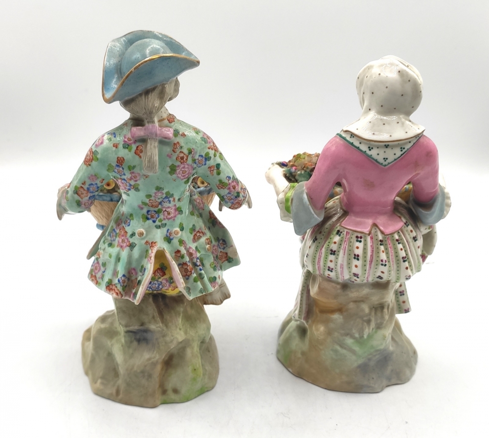 Pareja de figuras de jardineros con cestos de flores en porcelana policromada, con marca de espadas cruzadas