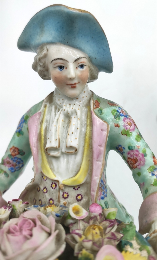 Pareja de figuras de jardineros con cestos de flores en porcelana policromada, con marca de espadas cruzadas