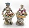 Pareja de figuras de jardineros con cestos de flores en porcelana policromada, con marca de espadas cruzadas