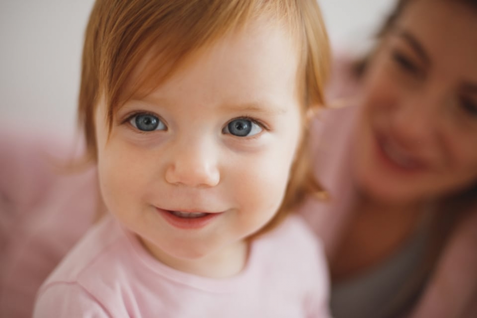 A smiling baby lying on a blanket.